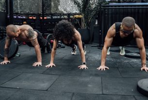 Three individuals performing push-ups together in a Mexico City gym setting.